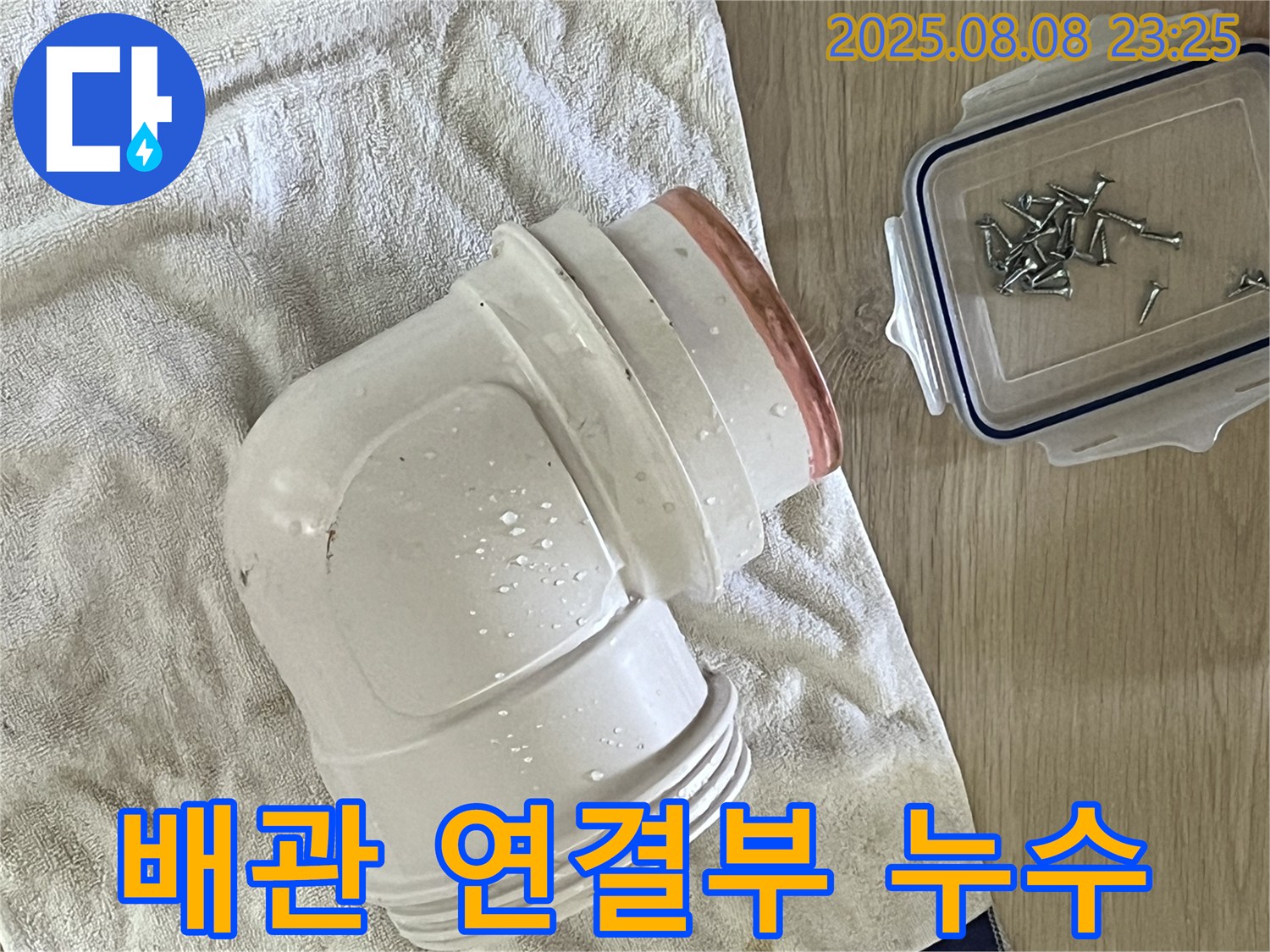 젖은 수건 위의 배관 연결부 - 연결 부위에서 누수가 진행 중인 모습입니다.
