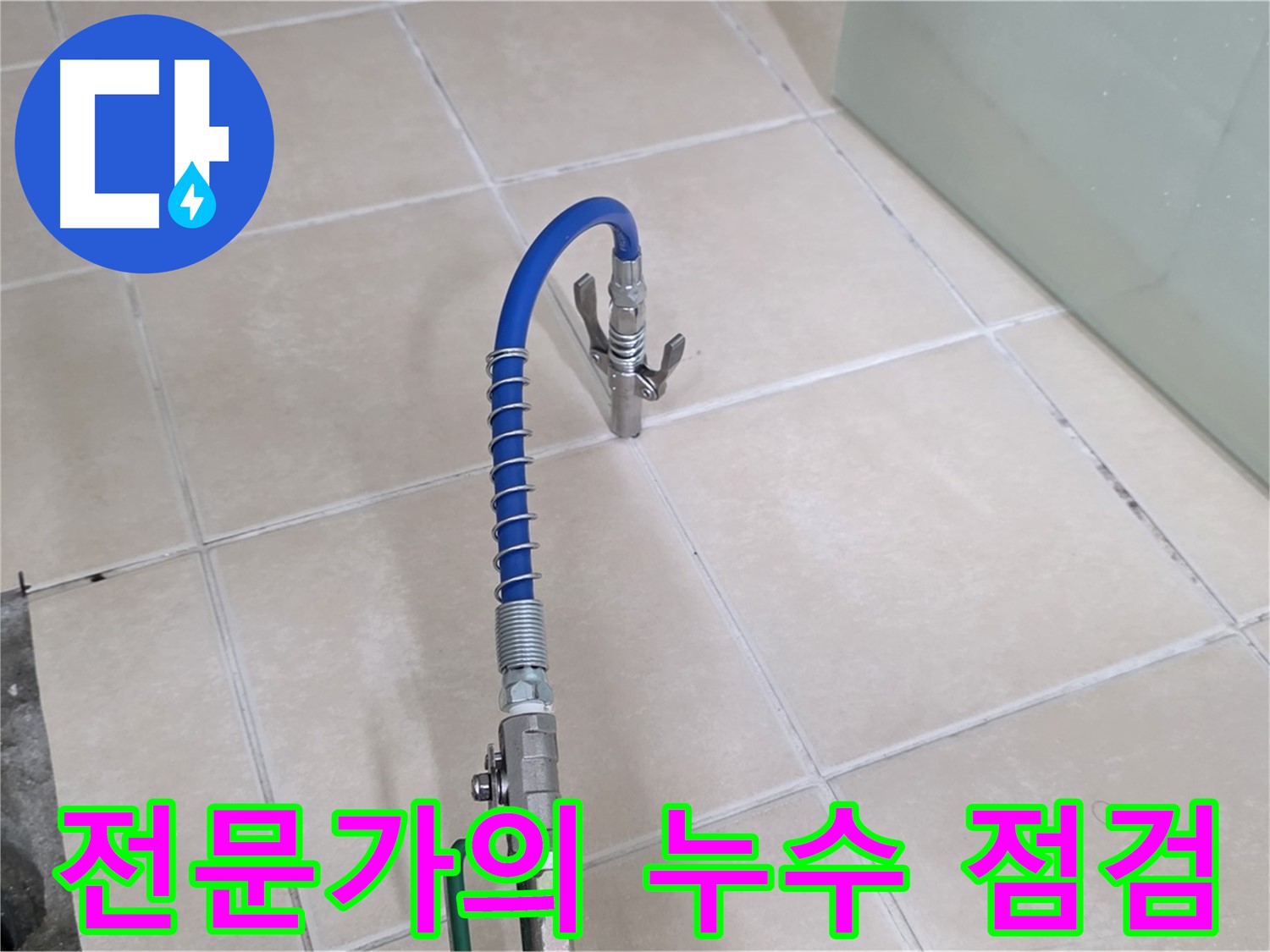 밝은색 타일 바닥에 놓인 파란색 호스와 배관 검사 도구