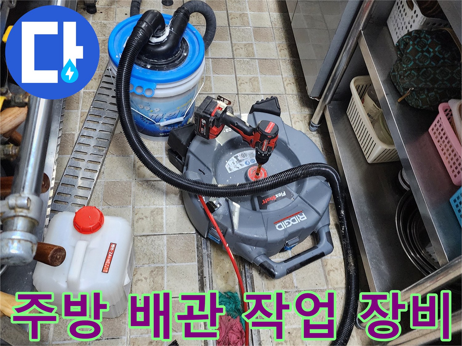 상가 주방 바닥의 배관 보수 작업을 위해 준비된 산업용 청소기와 각종 도구들