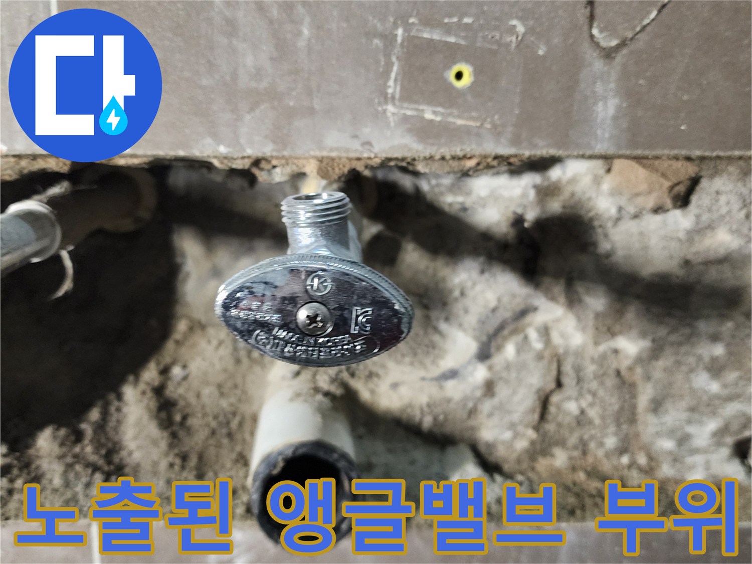 타일 안쪽으로 드러난 은색 밸브와 수도 배관 입구