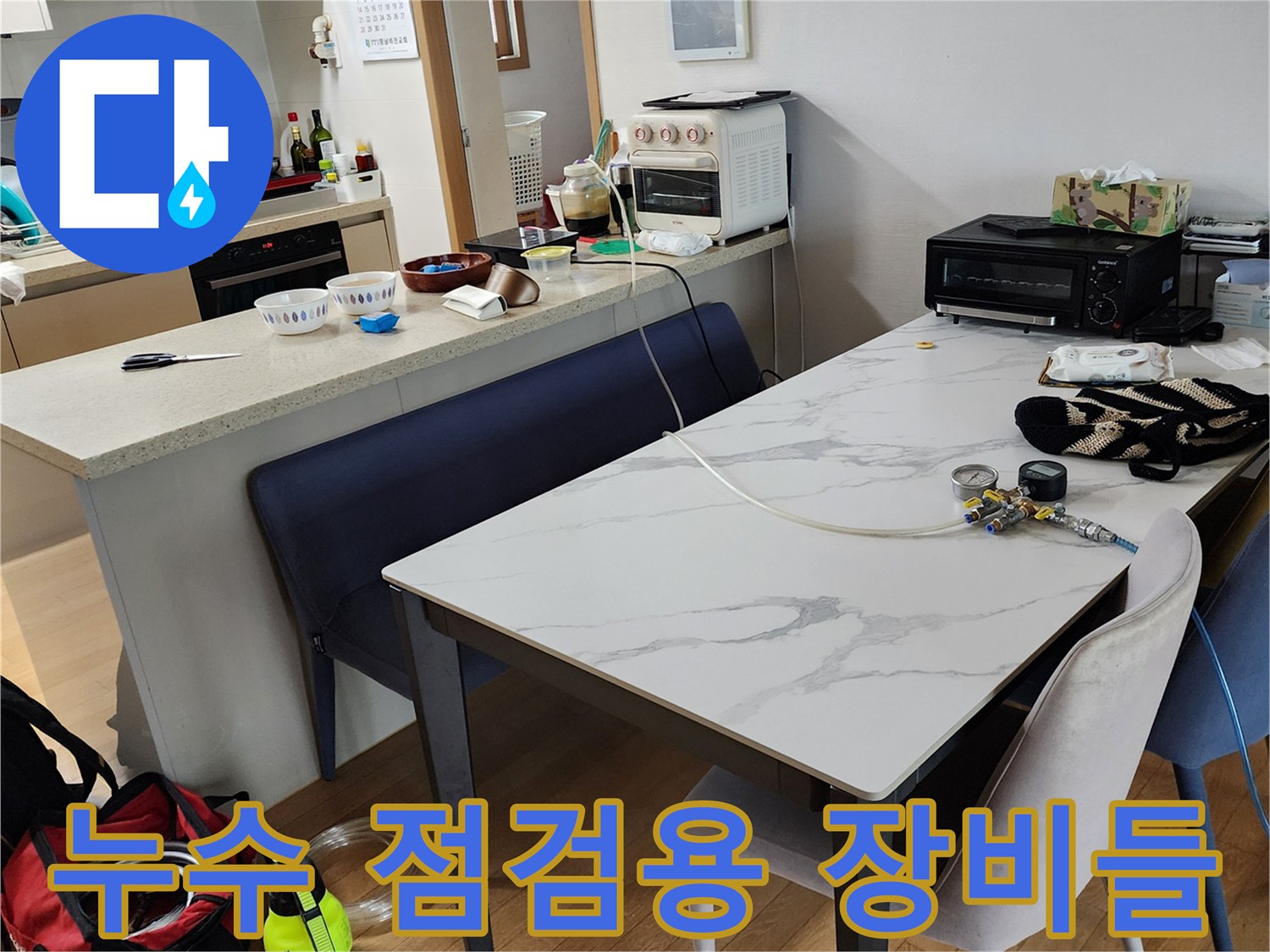 식탁 위에 놓인 압력계와 누수 진단용 부속품 세트