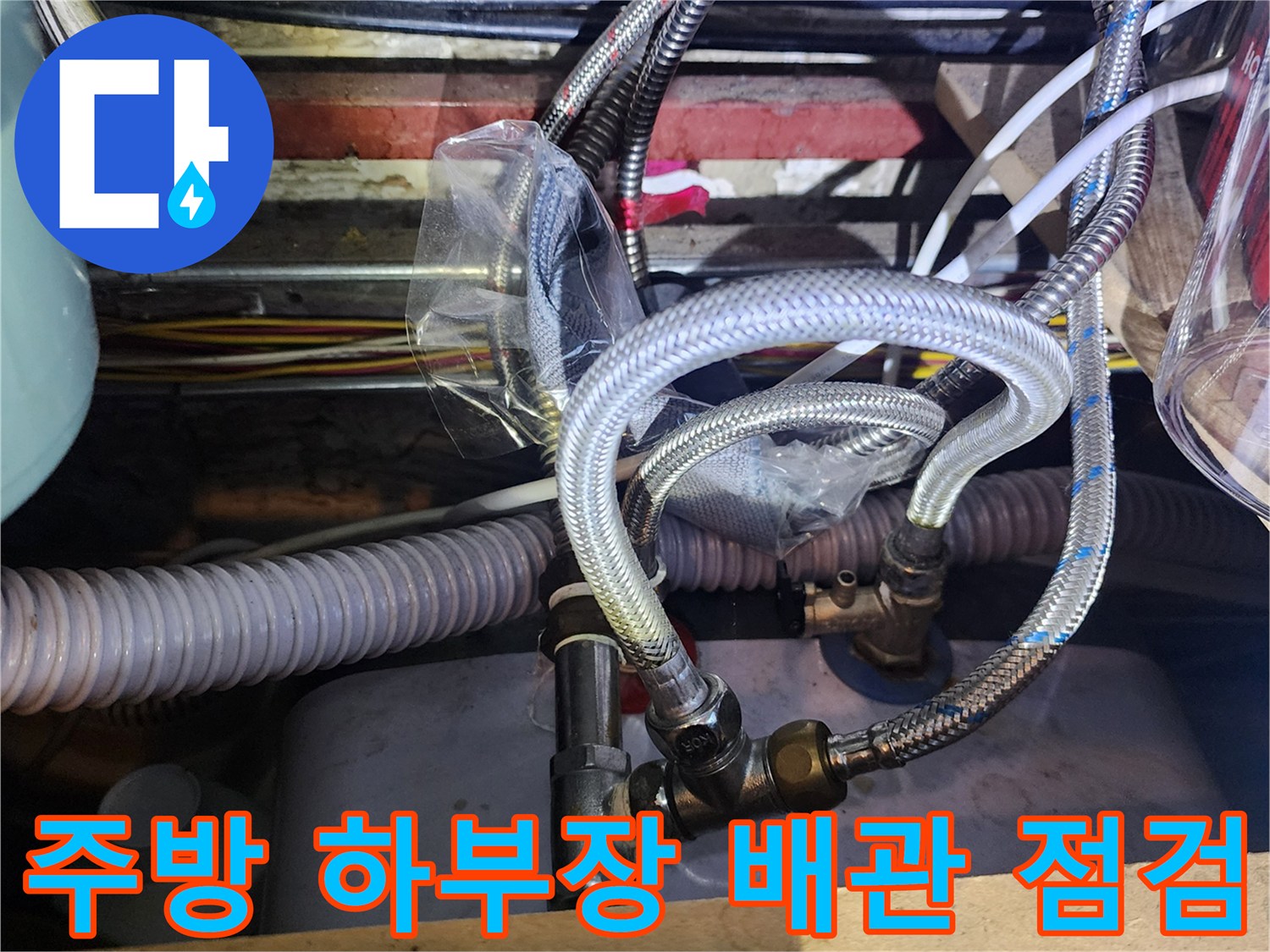 싱크대 밑 배관 연결 부위와 굵은 유연 호스가 복잡하게 지나가는 모습-배관 누수 진단 현장
