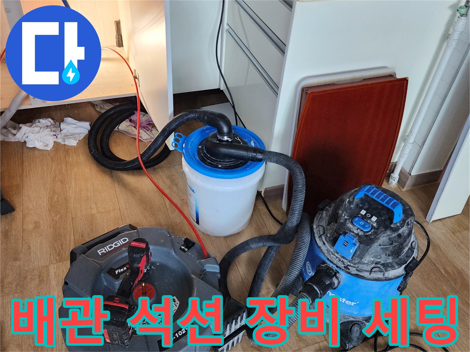 주방 싱크대 하부장 아래 배치된 배관 청소용 석션기와 보조 수거통