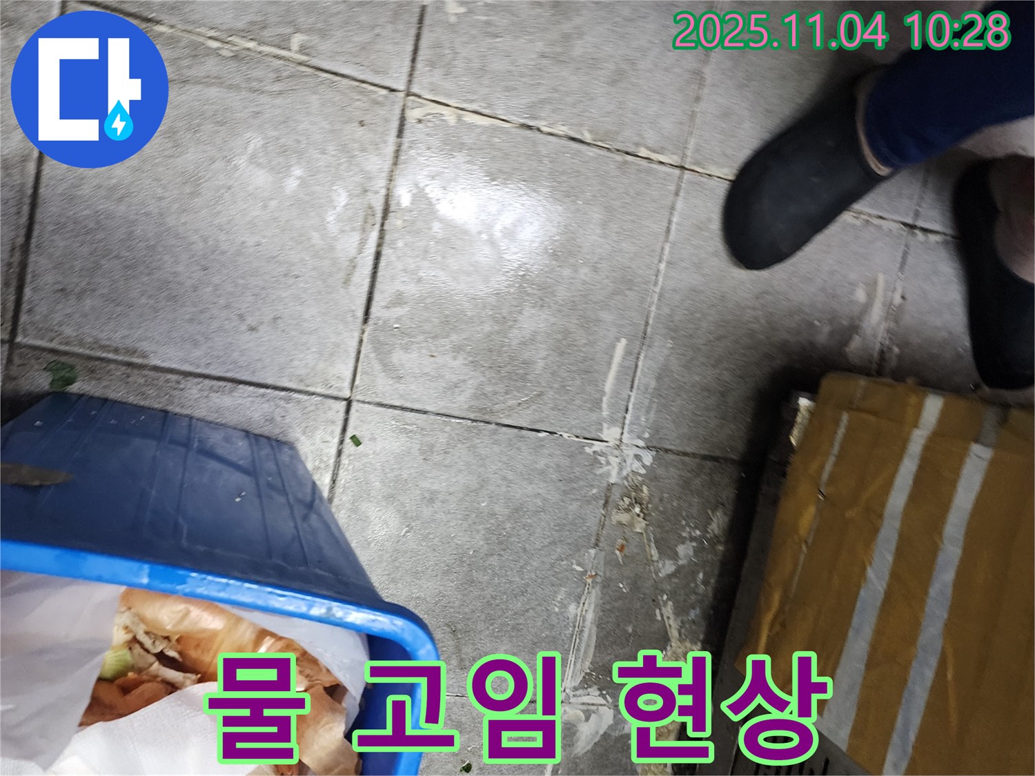 식당 바닥에 고여 있는 물 - 누수로 인해 발생한 물 고임 현상이며 - 미끄럼 사고를 유발할 수 있습니다.