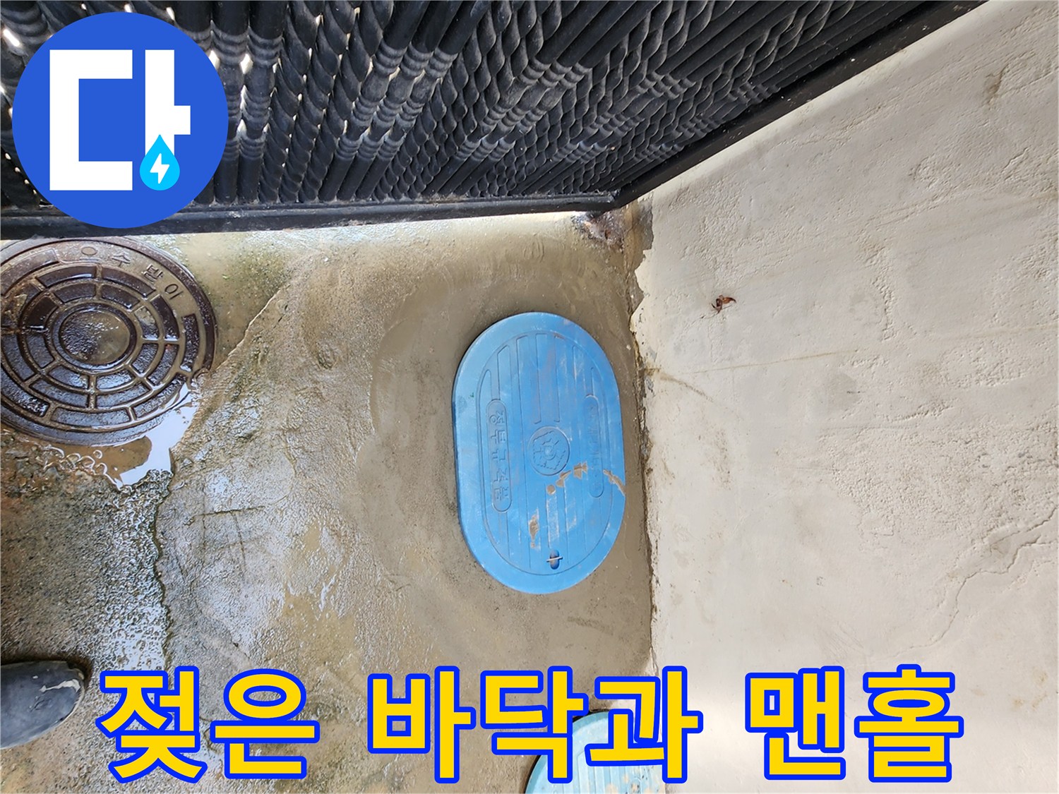 물기가 스며든 콘크리트와 파란 맨홀 뚜껑