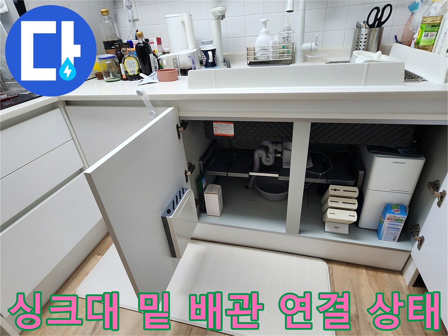 싱크대 하부장 내부의 배수 호스와 분배기 주변 환경 사진