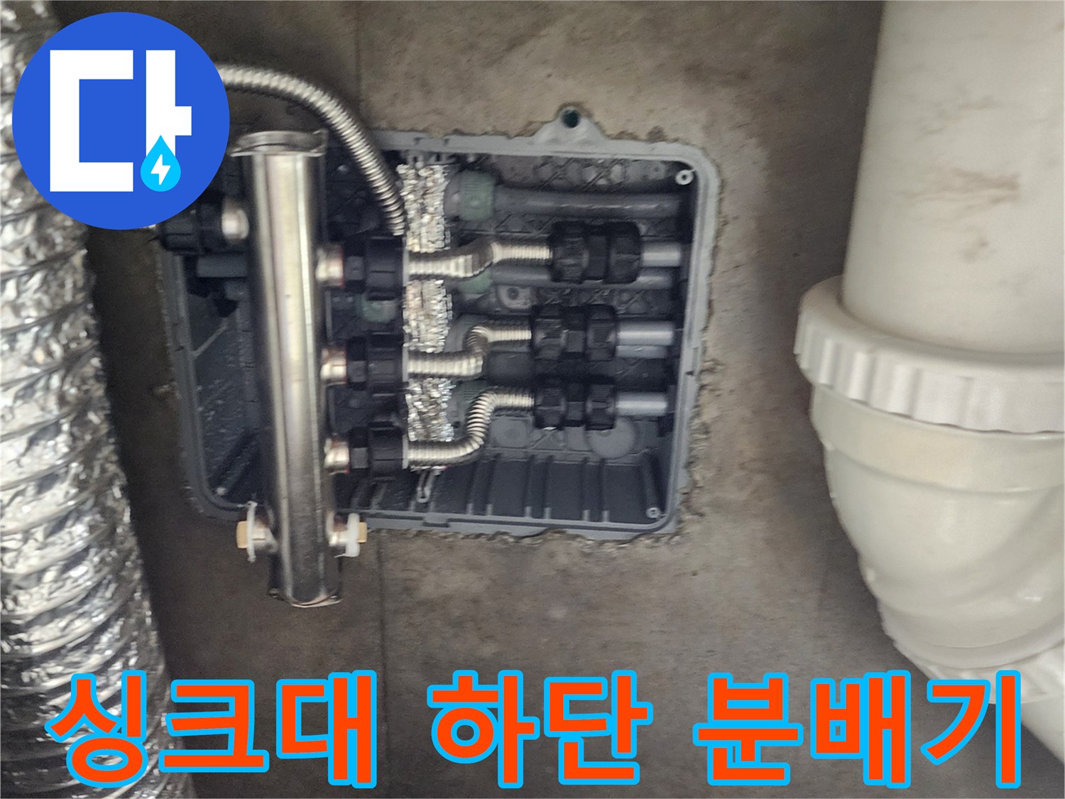 주방 싱크대 아래 매립된 스테인리스 분배기와 배관 연결 부위