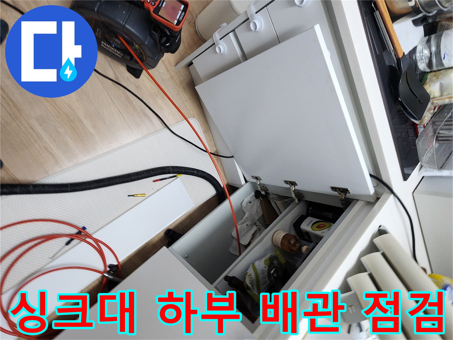 주방 싱크대 하부장에 내시경 카메라와 배관 장비를 배치한 모습