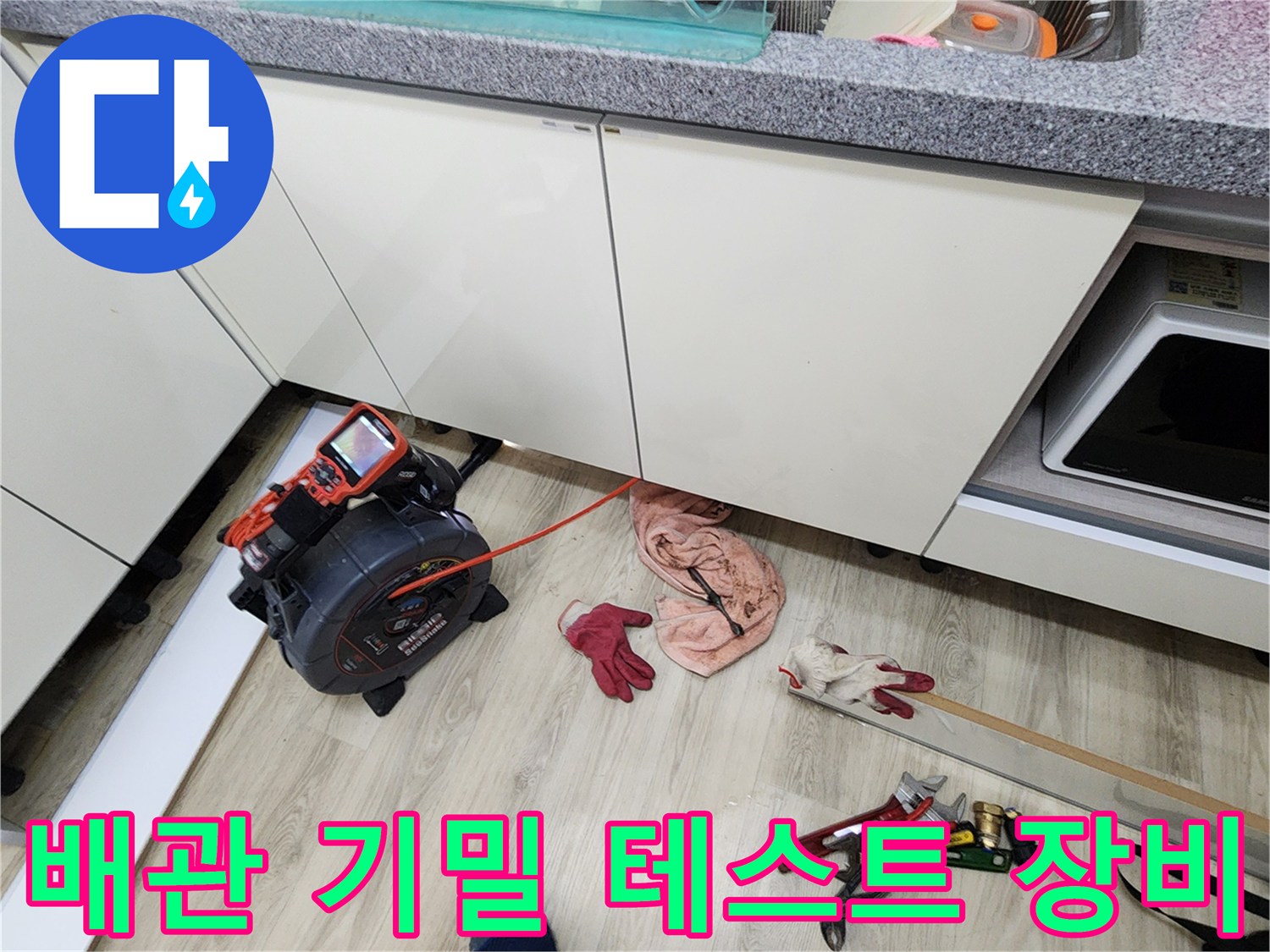 싱크대 아래 공간에 배치된 디지털 압력 측정기와 작업용 장갑 및 공구