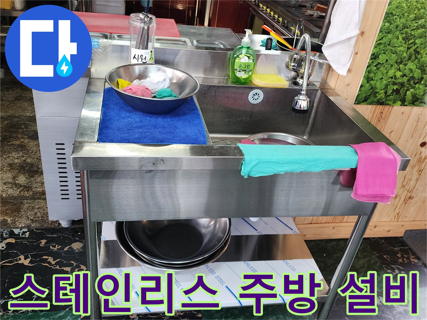 스테인리스 재질의 조리대와 싱크대가 설치된 주방 내부입니다.
