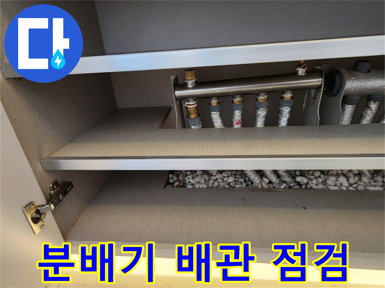 싱크대 하부 선반 아래 분배기와 보온재 배관의 모습입니다.
