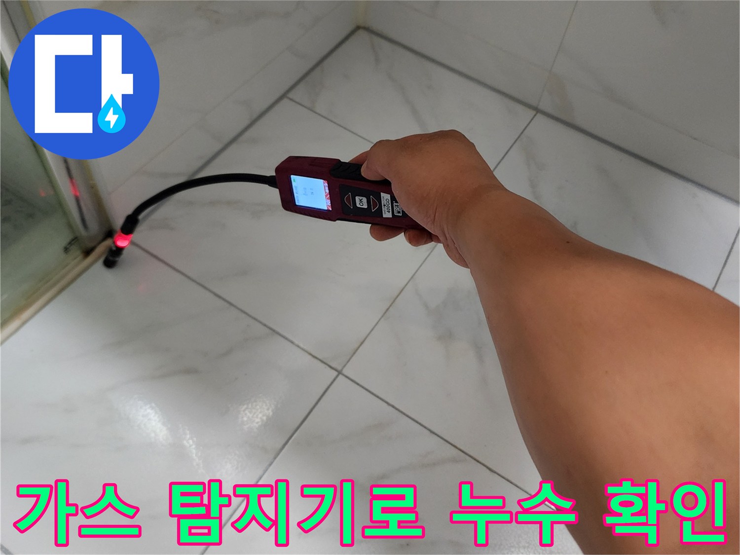 배관 가스를 감지하는 탐지기를 타일 틈새에 대고 있는 모습입니다.