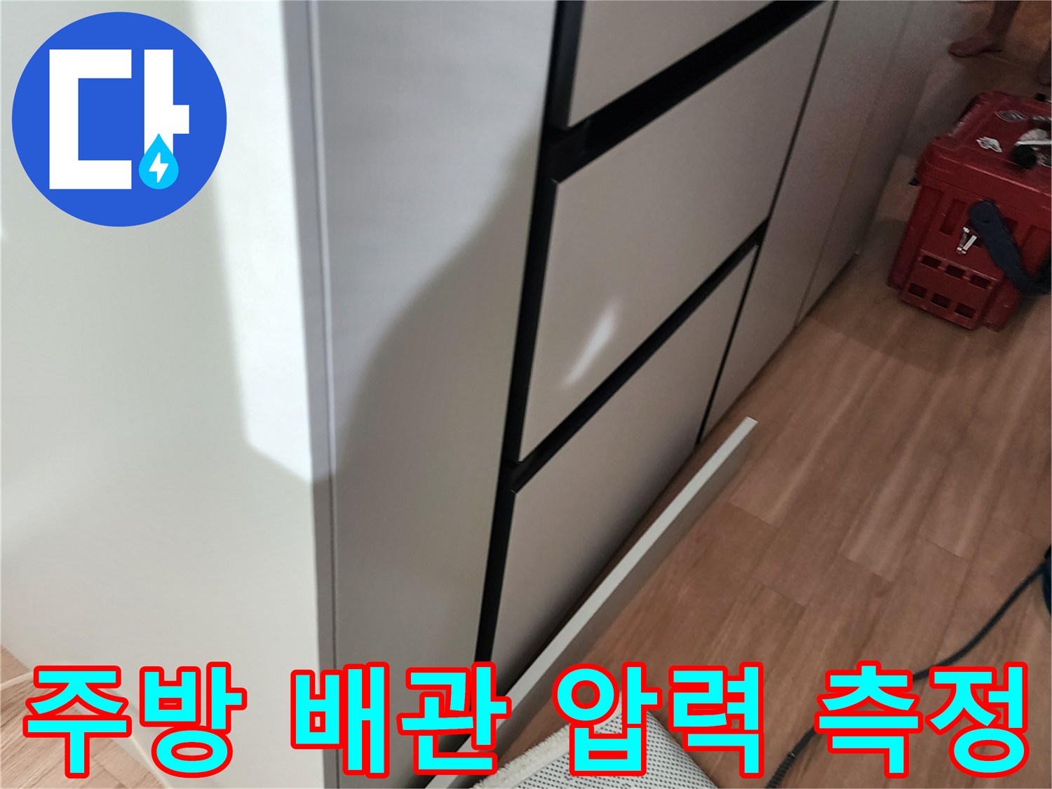 하얀색 싱크대 하부장 아래로 보이는 배관과 연결된 호스