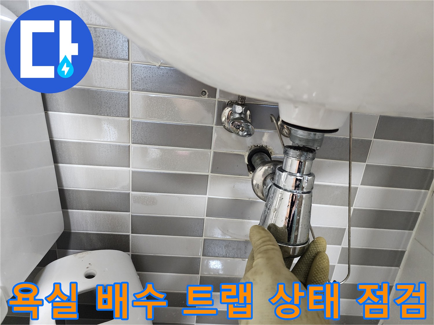 세면대 하단 크롬 배관의 연결 부위를 손으로 만지는 엔지니어의 작업 장면