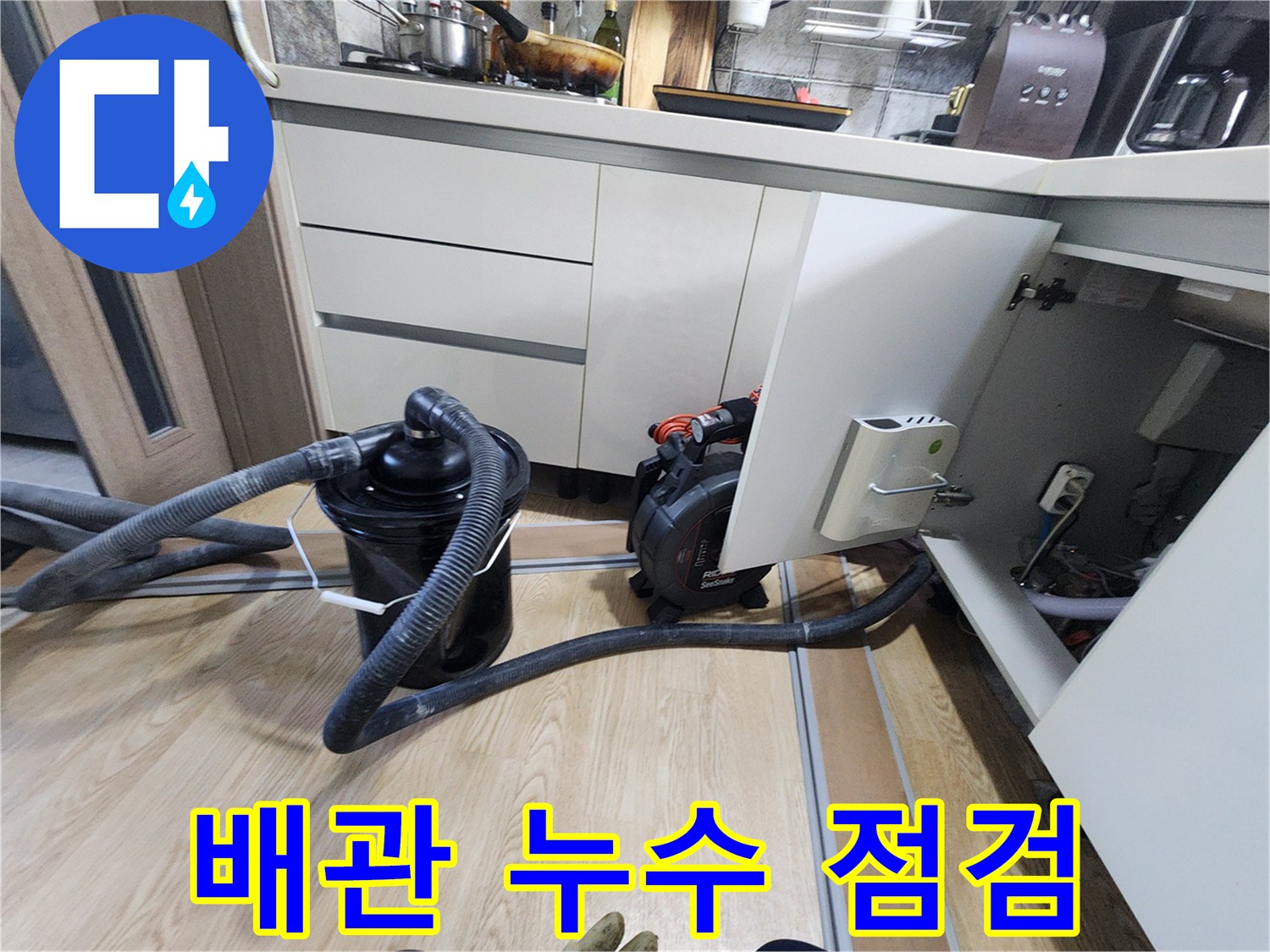싱크대 아래쪽 배관 주변의 물기를 제거하고 상태를 확인하는 작업 현장