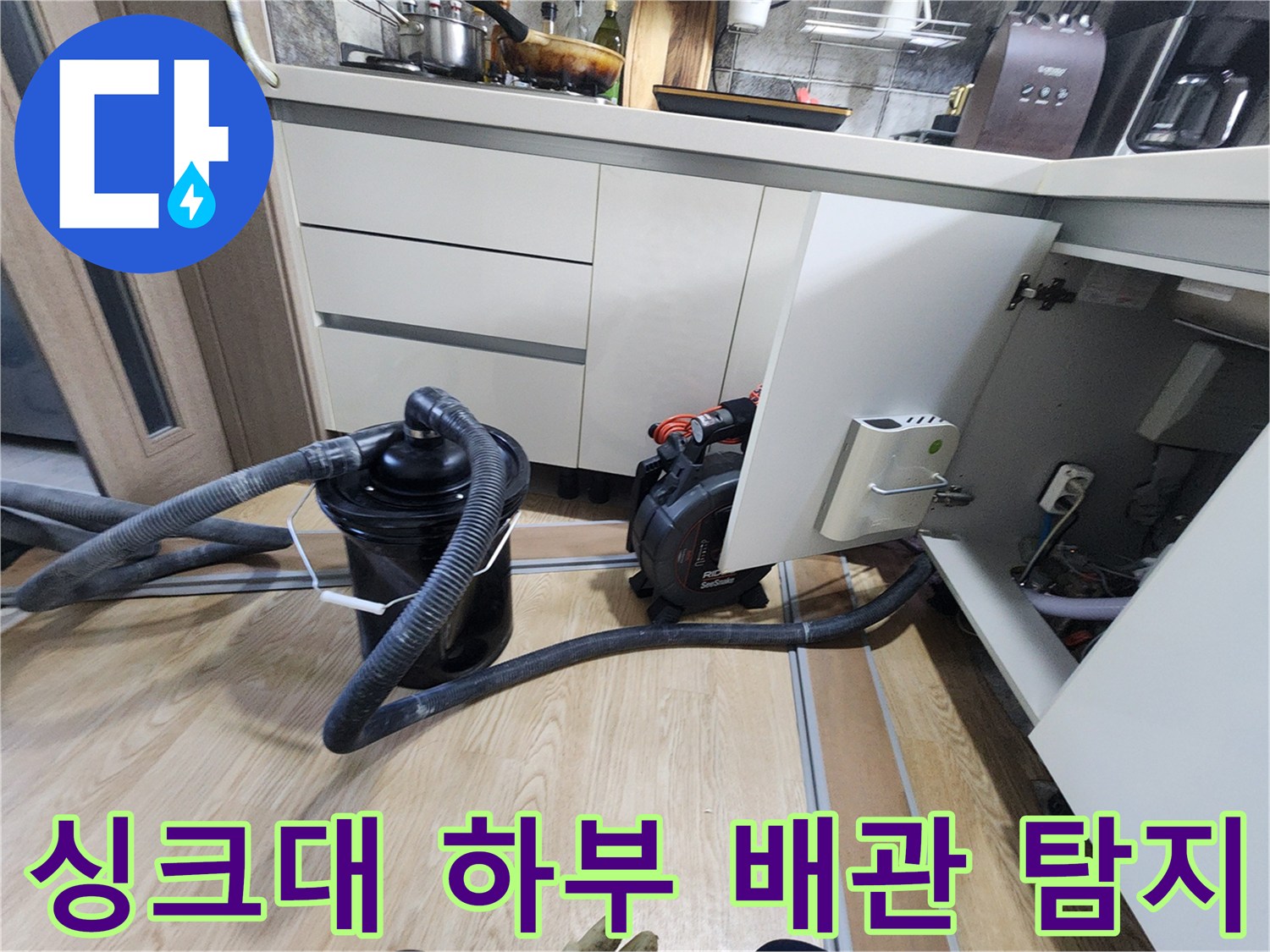 싱크대 하부장 바닥 공간에 설치된 배관 점검용 장비와 호스
