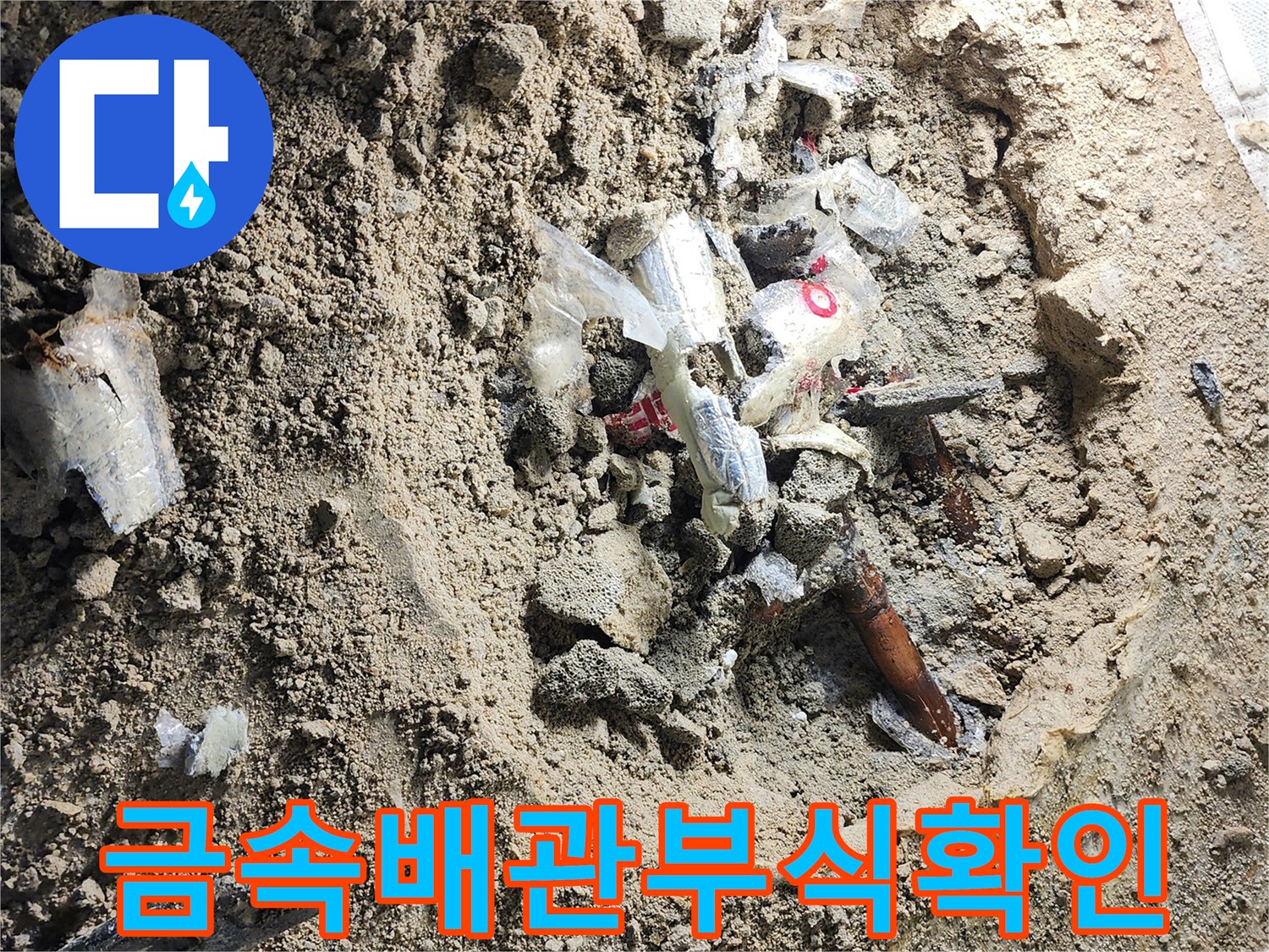 흙과 파편 사이로 드러난 부식된 금속 배관의 연결 지점