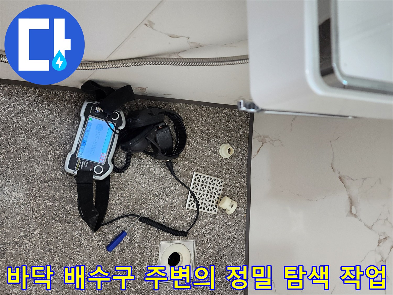 배수구 주변 타일 바닥에 놓인 가스식 탐지기와 점검 도구들