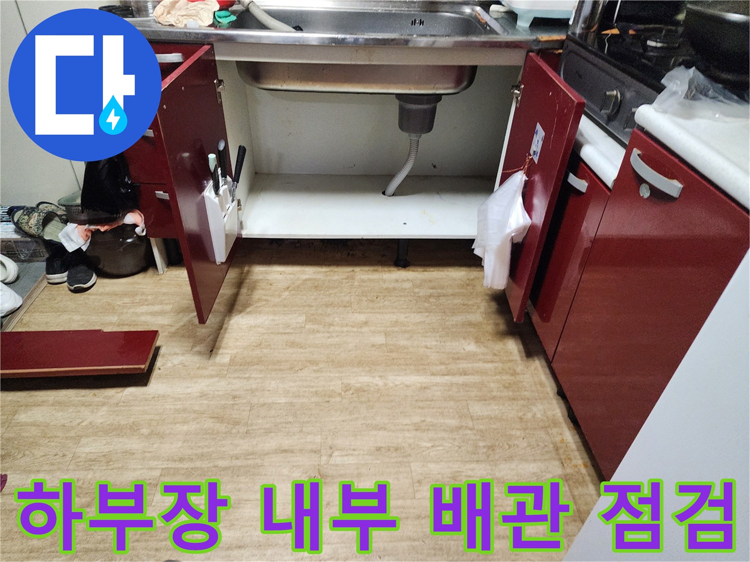 싱크대 하부장 문을 열고 배관 주변의 습기를 확인하는 모습