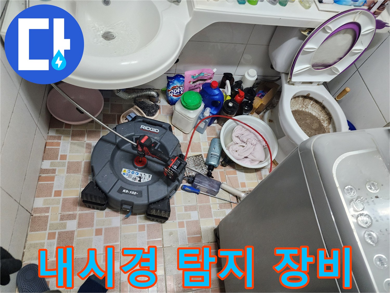 욕실 바닥에 배치된 배관 점검용 리지드 내시경과 세척 도구들