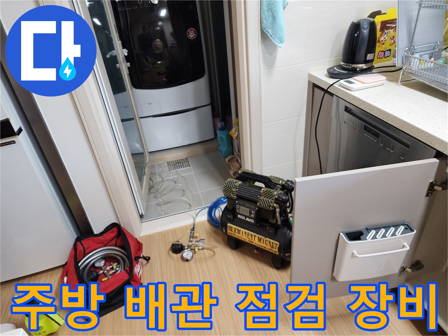 싱크대 하부장 근처에 놓인 배관 세척용 컴프레셔와 작업 도구들