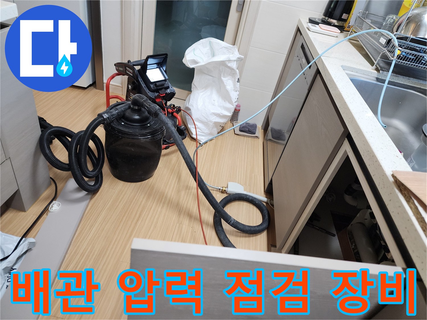싱크대 밑 공간에 설치된 배관 압력 테스트용 호스와 게이지 연결 부위