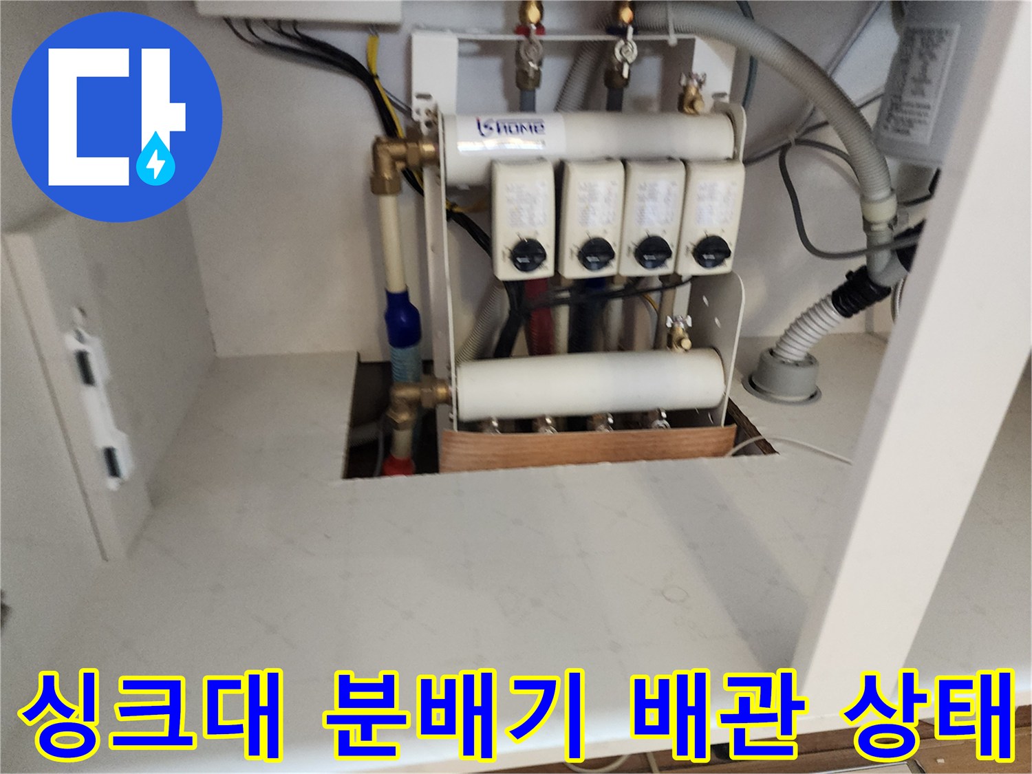 주방 싱크대 하부장 내부의 수도 분배기와 연결 배관 모습입니다.