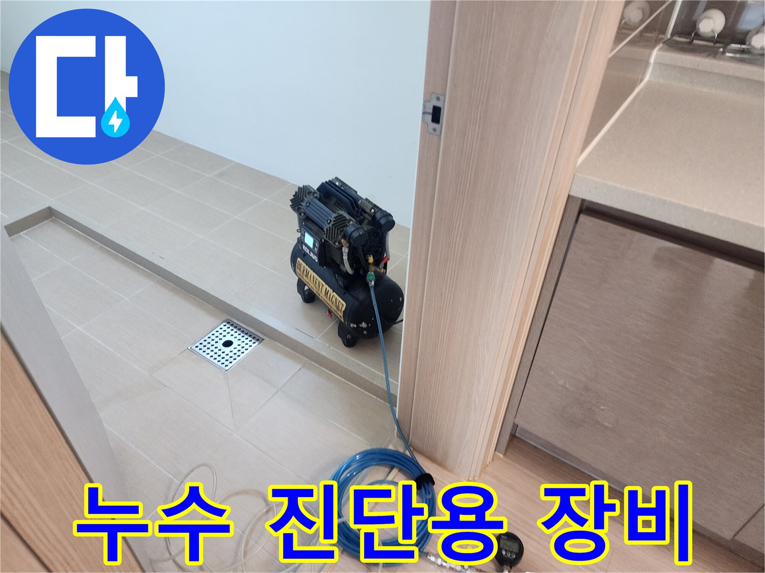 욕실 바닥 배수구와 연결된 공압 테스트기 및 파란색 호스