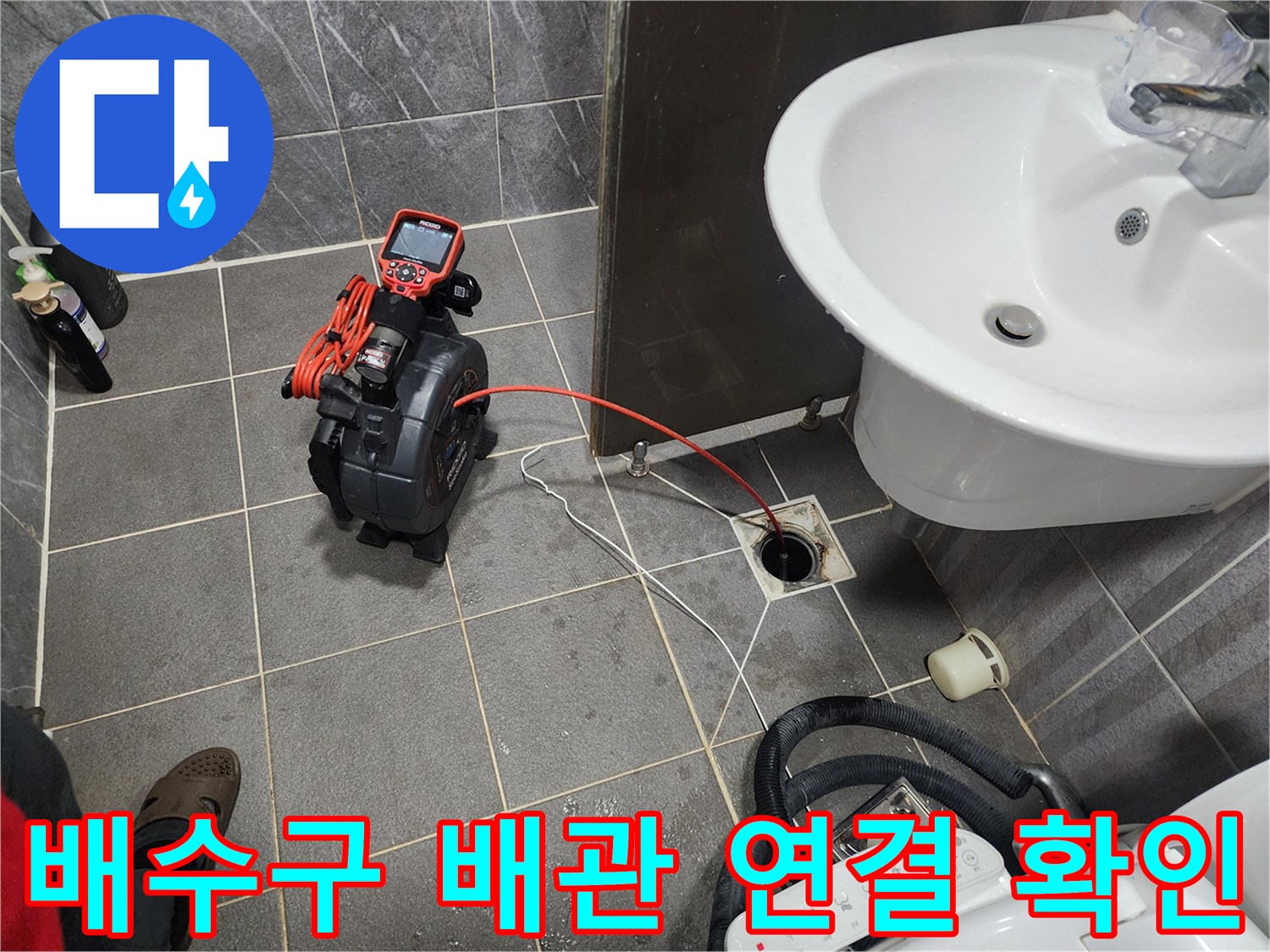 타일 바닥 배수구와 연결된 빨간색 호스와 수치 표시 장치