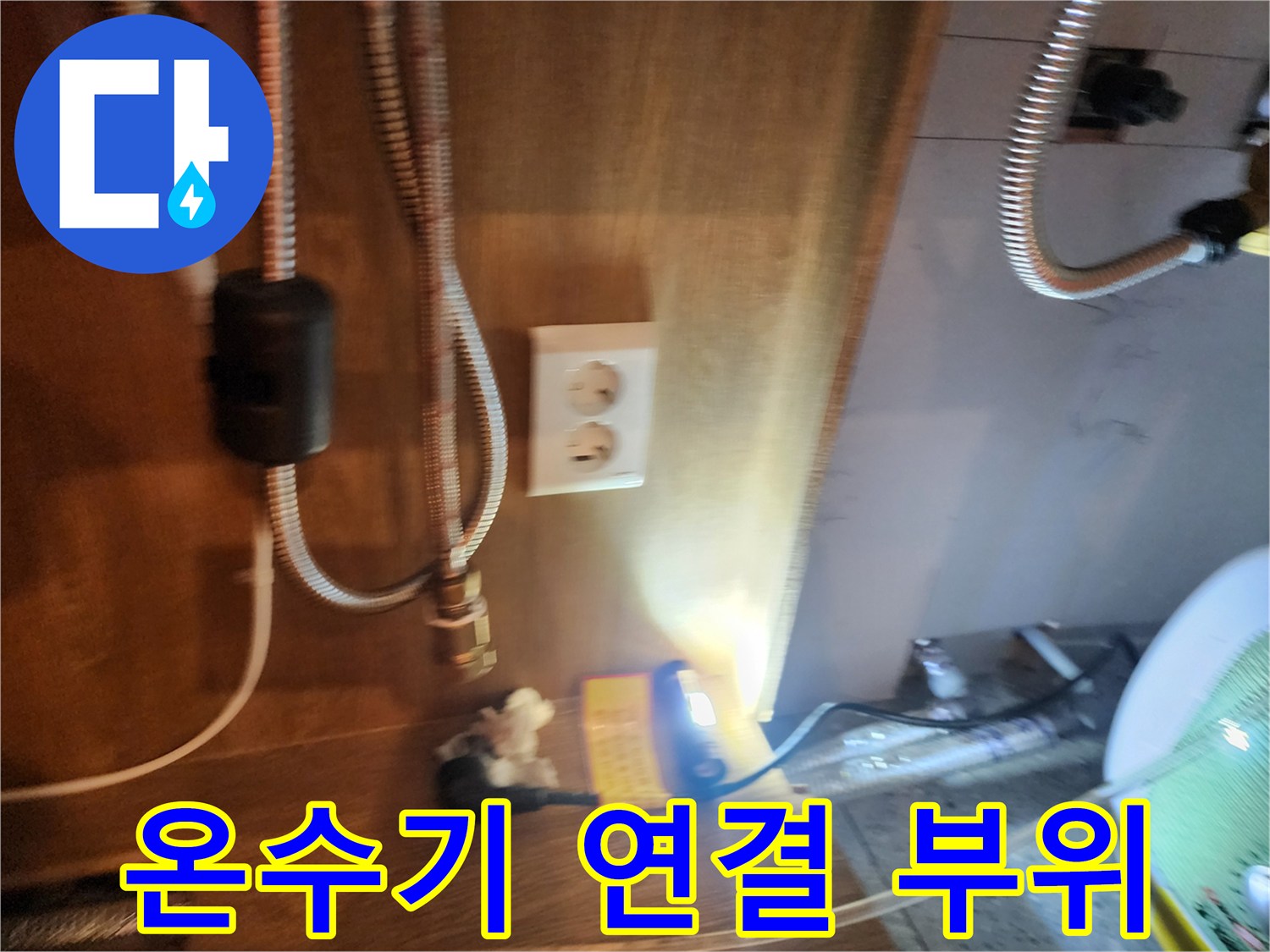 전기 온수기 하단에 연결된 은색 스테인리스 호스 사진