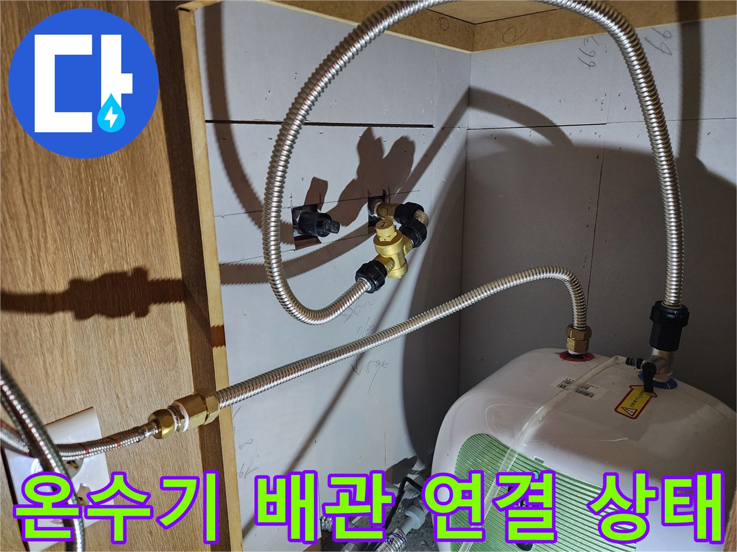 전기 온수기와 은색 금속 호스가 결합된 부분의 근접 촬영