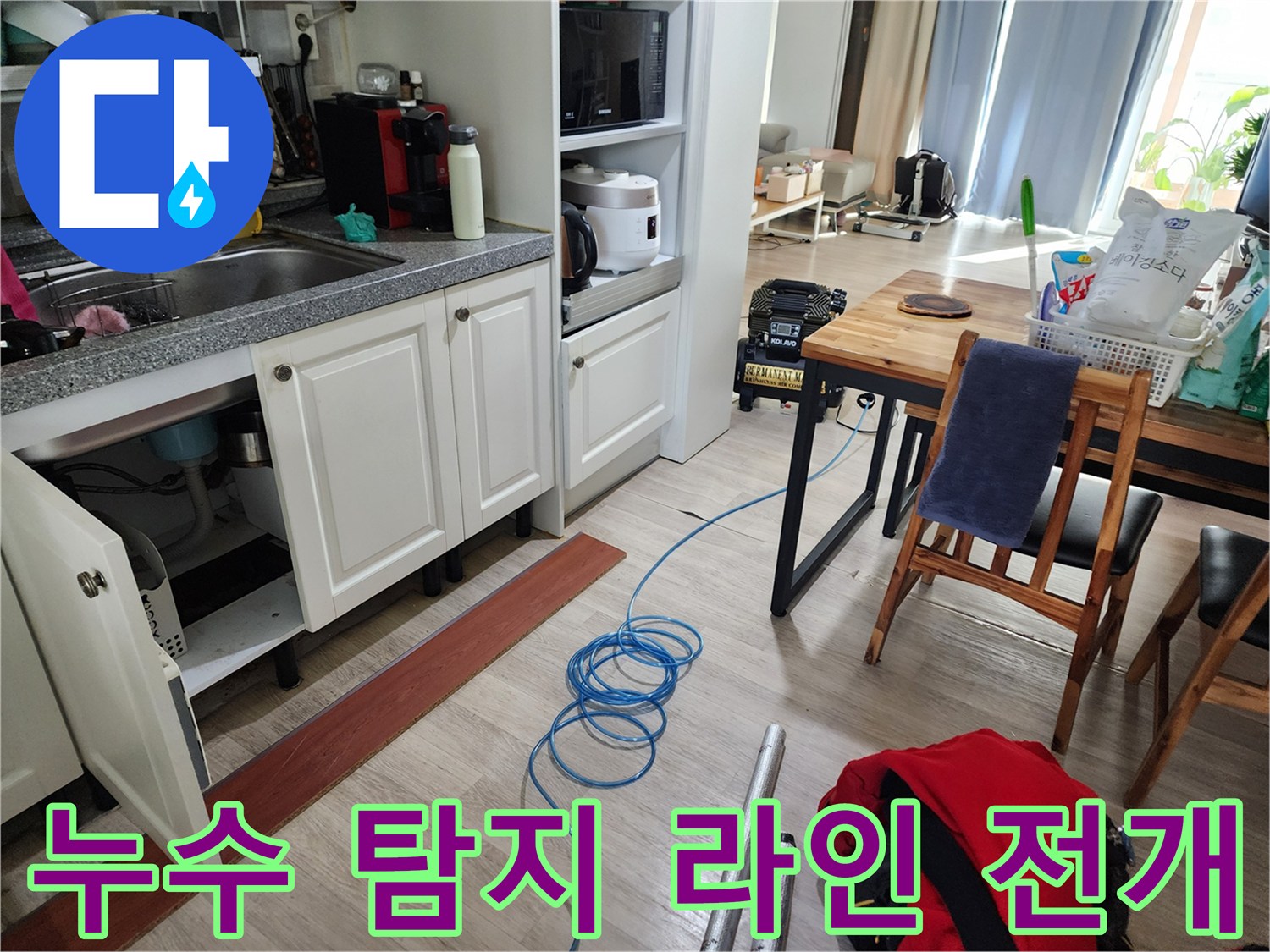 싱크대 하부 바닥에 설치된 파란색 가스 호스와 작업 도구들
