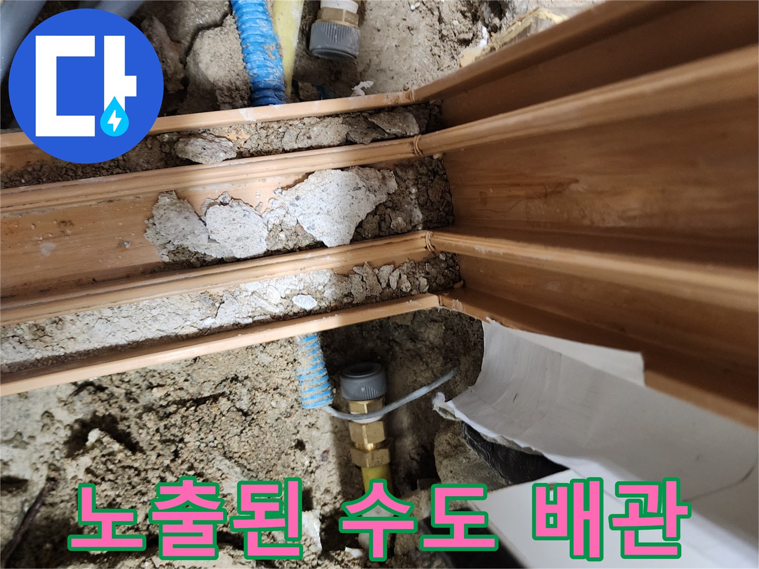흙과 콘크리트 사이로 드러난 노란색 및 파란색 배관