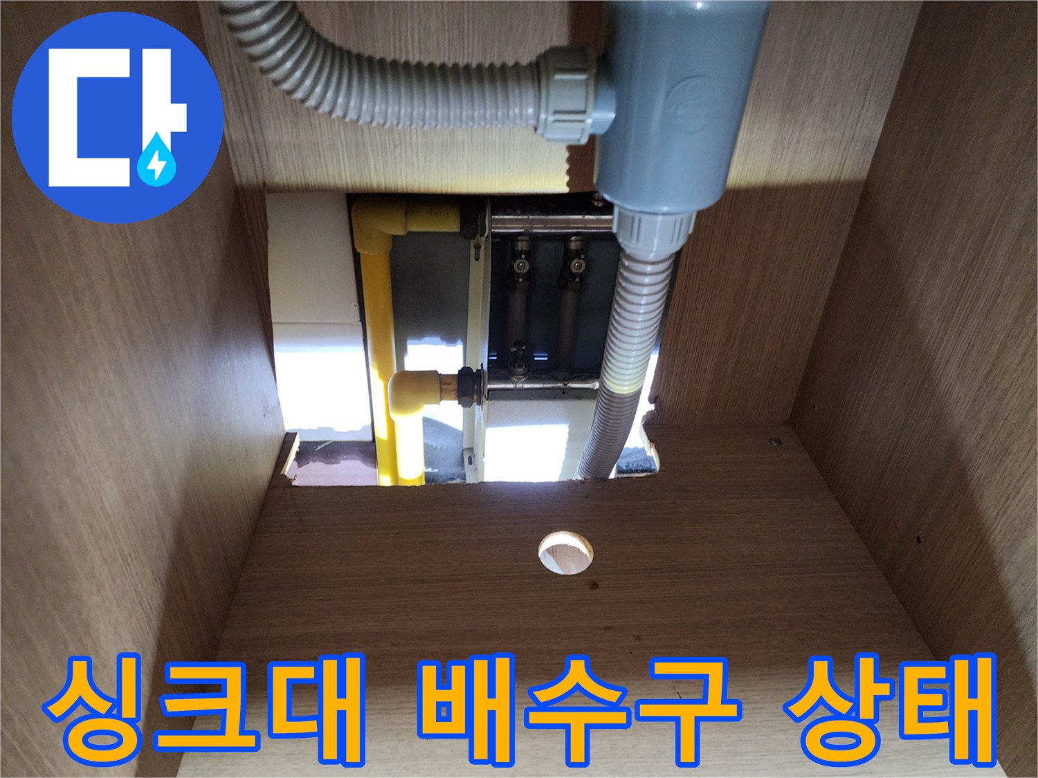 싱크대 하부장 내부의 배수 호스와 분배기 연결 부위 모습