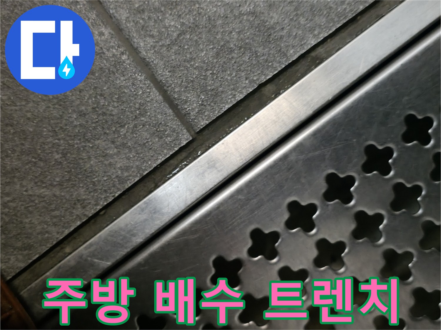 스테인철 소재의 배수 트렌치 덮개와 인접한 회색 타일