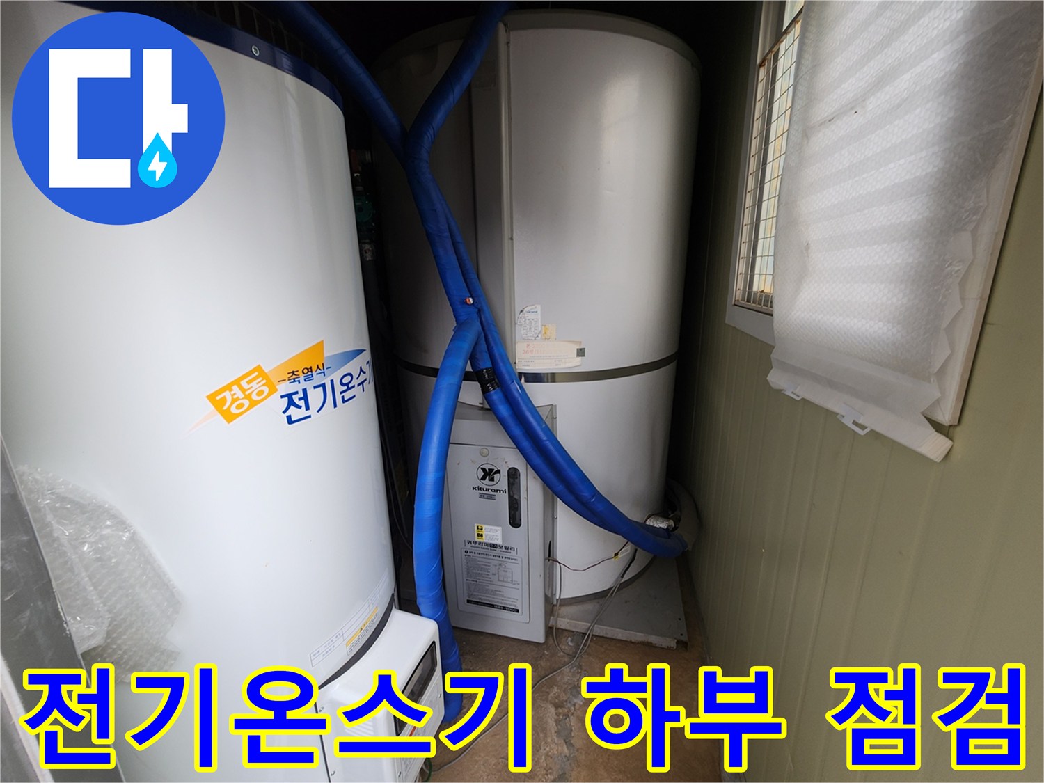 파란색 보온재로 감싸진 배관이 대형 온수 탱크에 연결되어 있습니다.