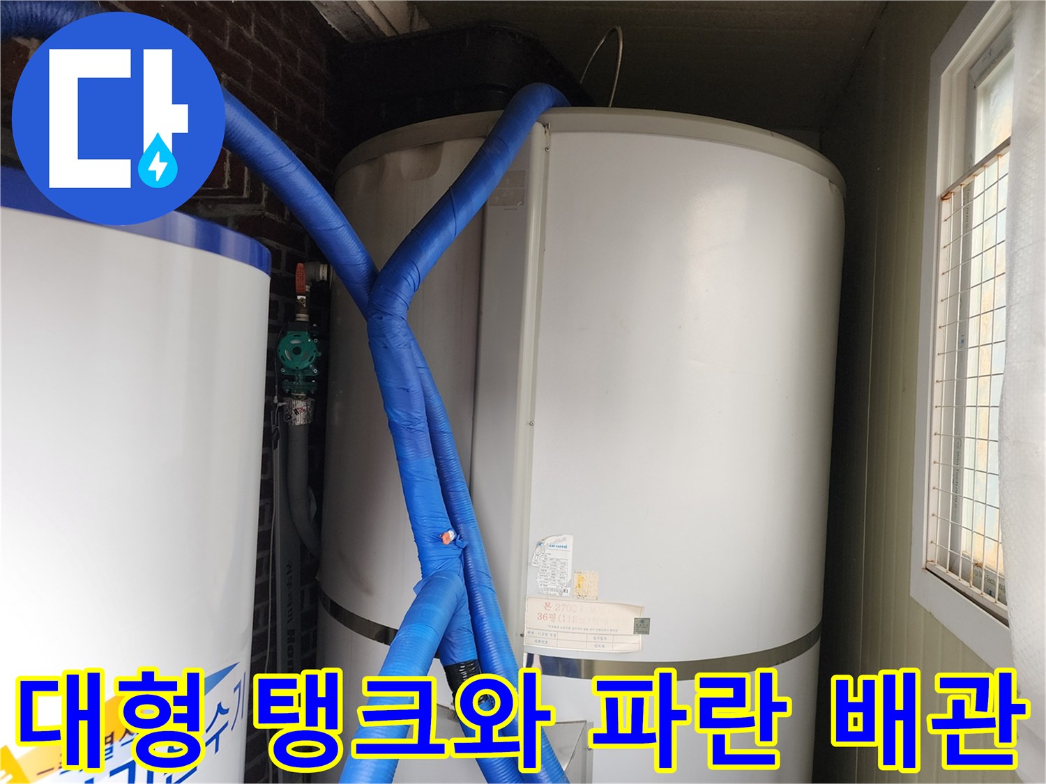 흰색 탱크로 연결된 파란색 보온 배관의 근접 촬영입니다.