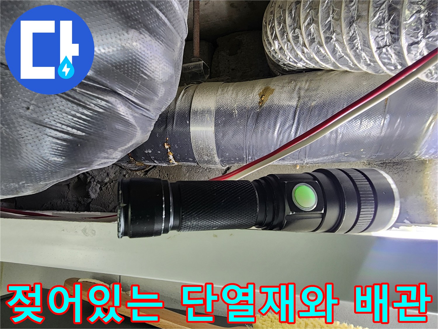 손전등 빛에 비춰진-습기를 머금은 은박 단열재와 배관 연결부