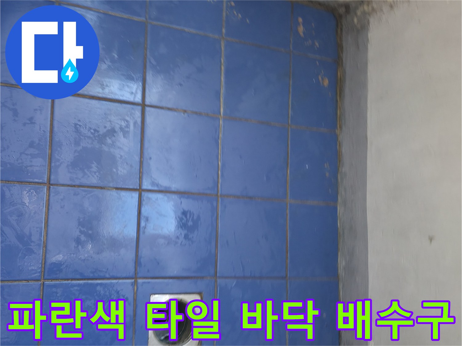 세탁실 바닥의 파란색 타일과 중앙에 위치한 배수구 구멍