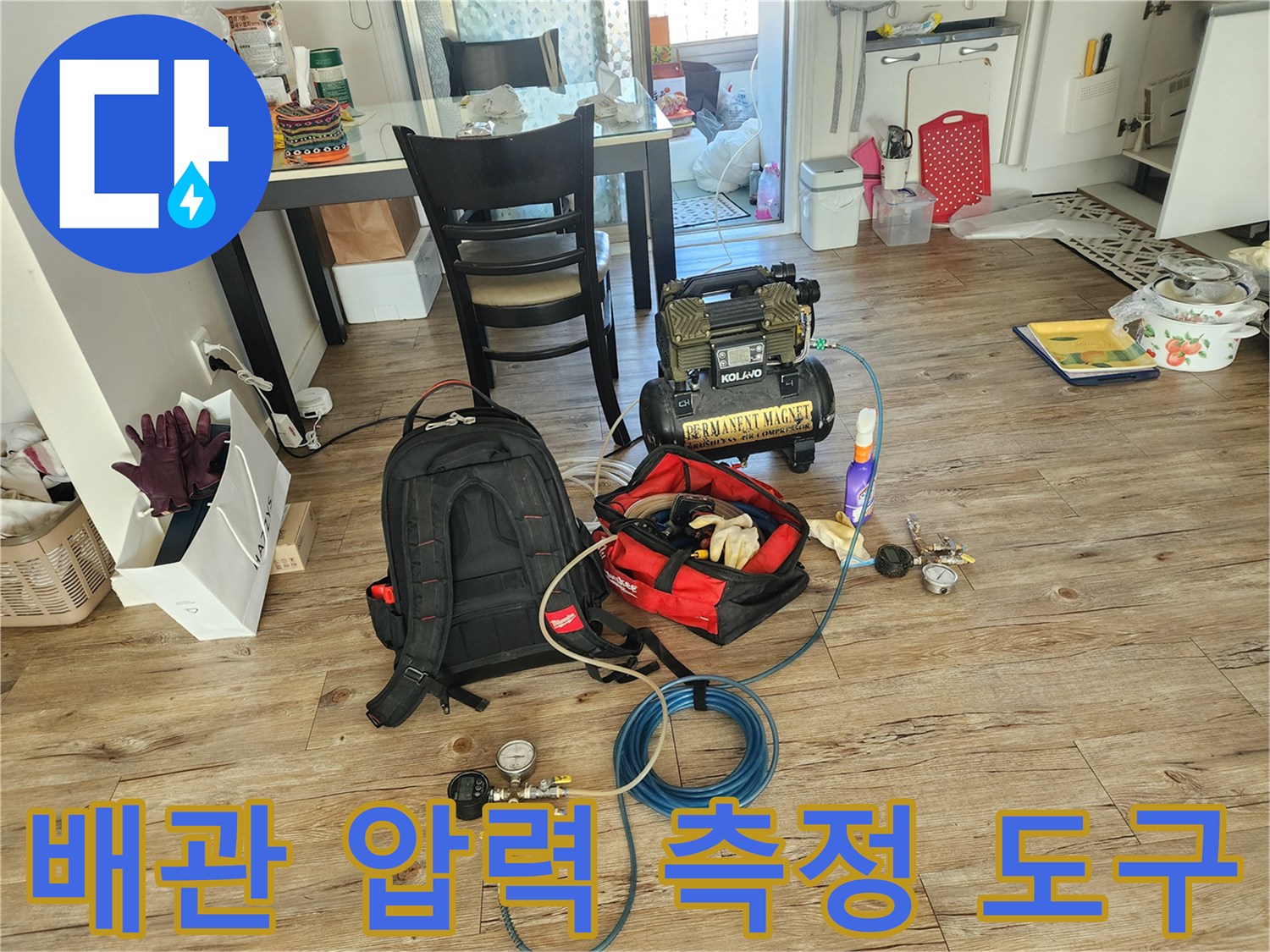 누수 지점을 찾기 위해 거실 바닥에 배치된 공기압 테스트용 컴프레셔와 게이지