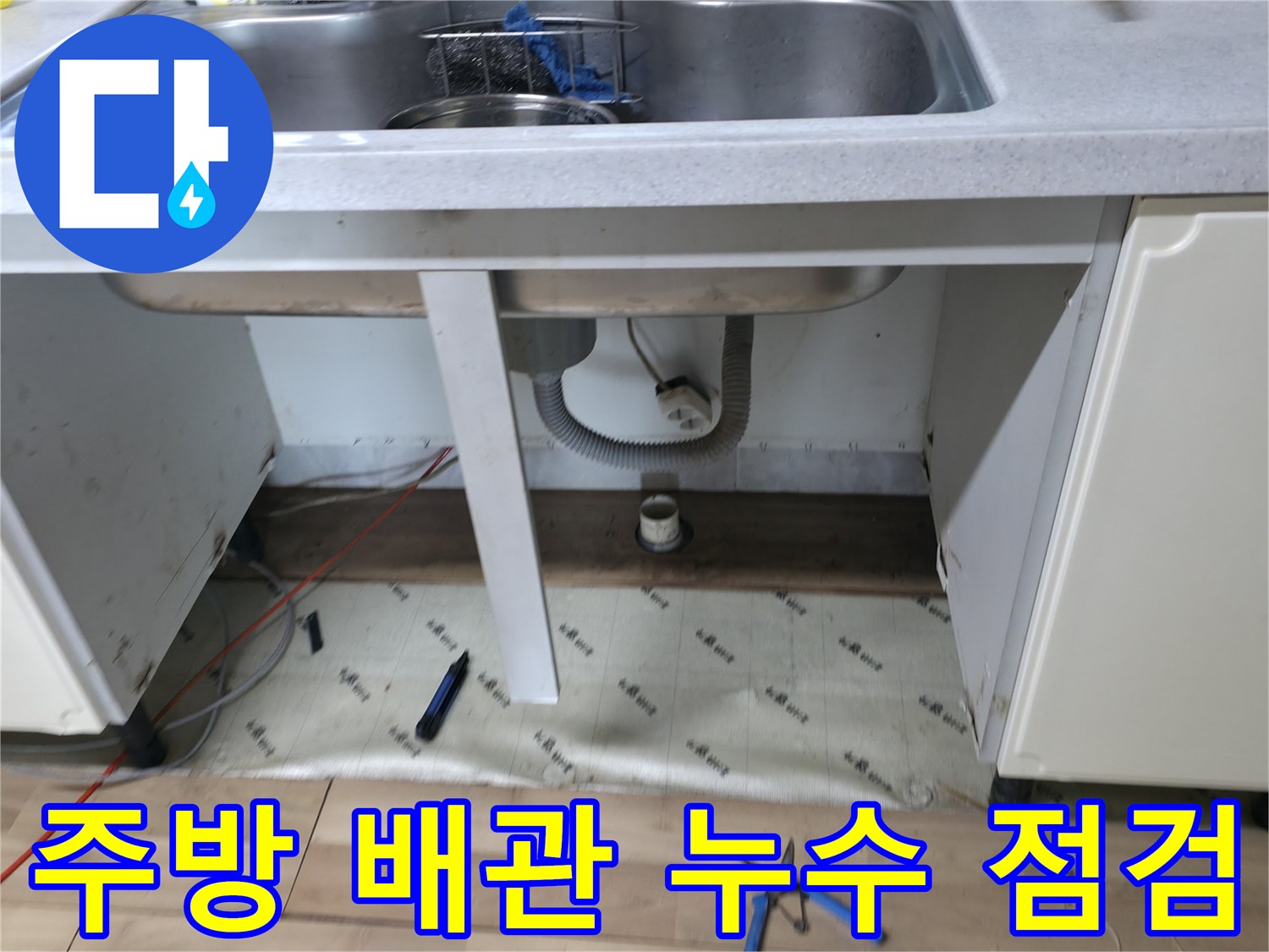싱크대 하부장 내부의 배수관과 수도 배관 연결 부위 상세 사진