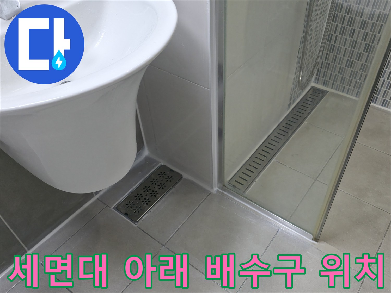 화장실 세면대 하단부와 바닥 배수 유가 근접 촬영 사진입니다.