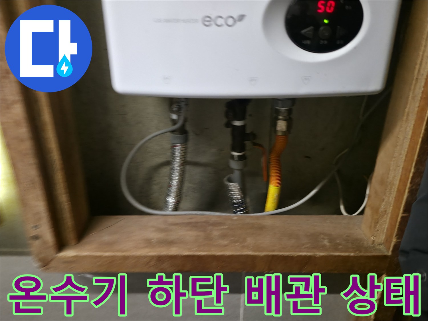 전기 온수기 아래에 연결된 은색 주름관과 노란색 호스 배관 모습