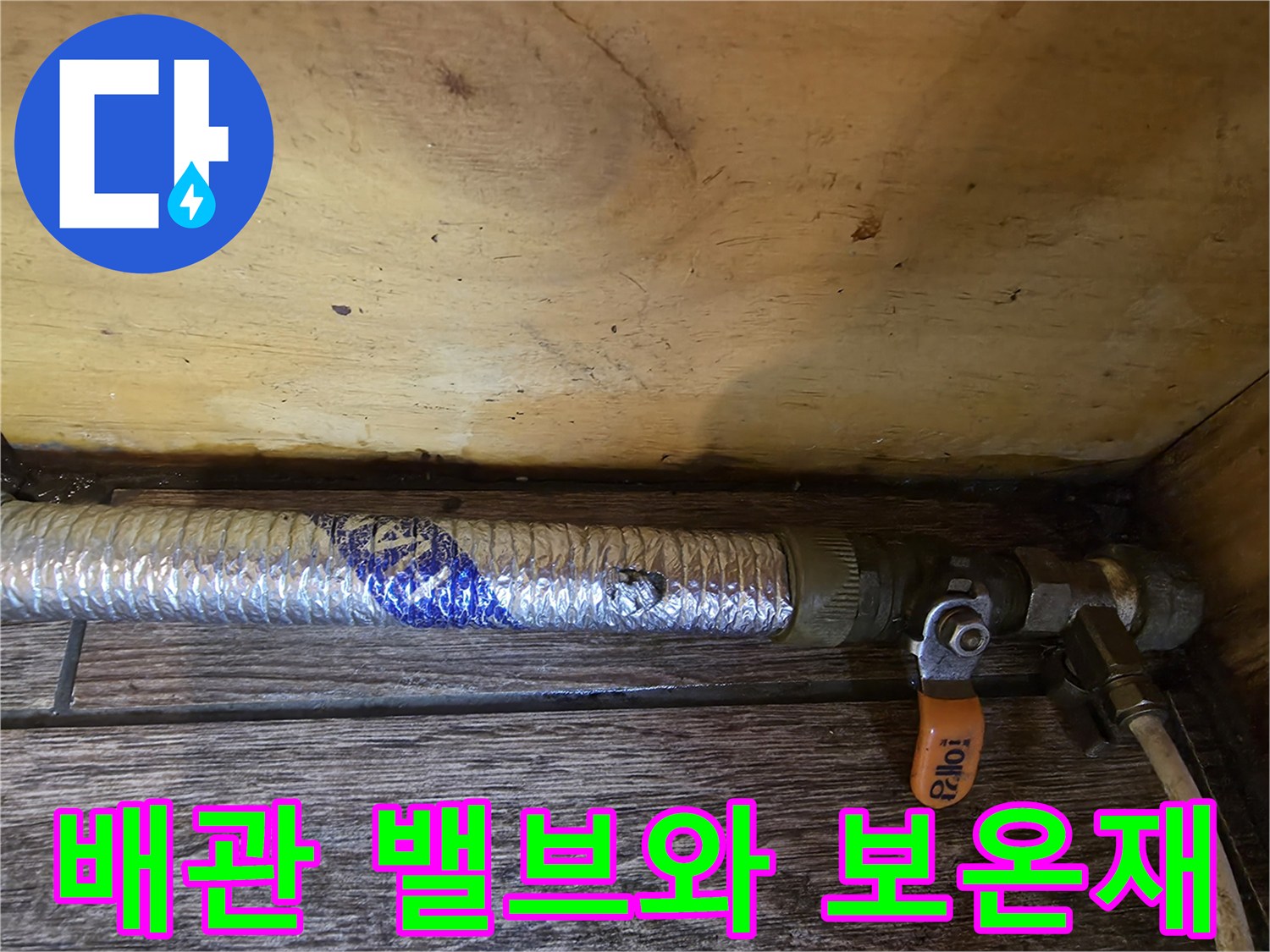 주황색 밸브 손잡이와 은박 보온재로 덮인 배관 연결 부위