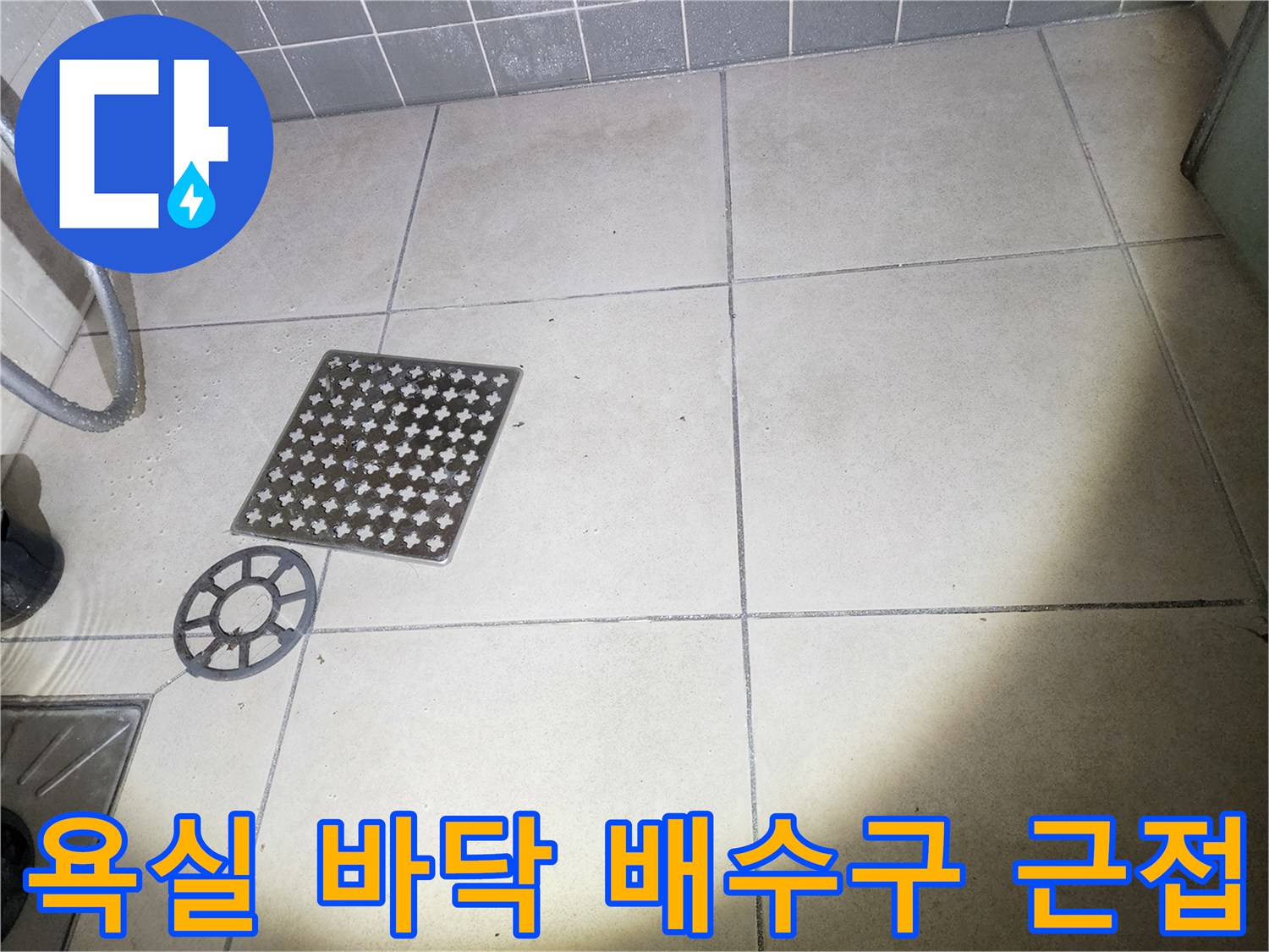 화장실 내부의 격자형 배수 덮개와 주변 타일 면입니다.