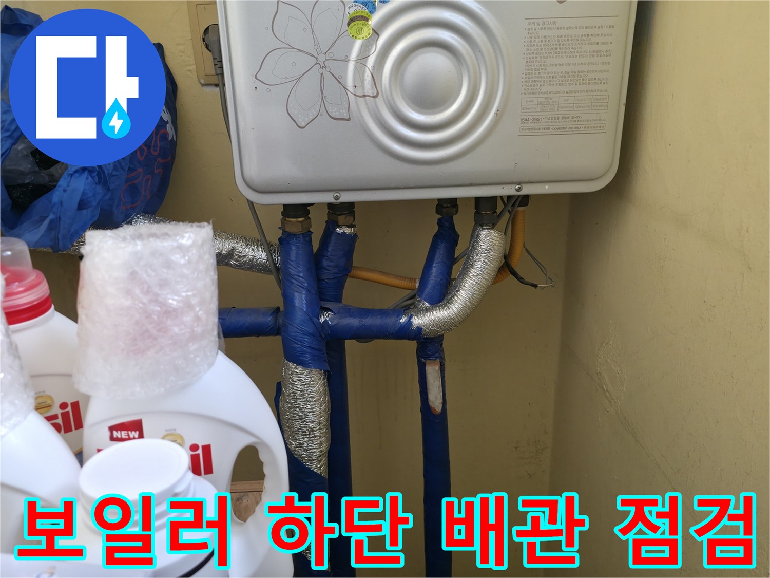 보일러 하단의 파란색 배관과 은박 보온재가 씌워진 배관의 모습입니다.