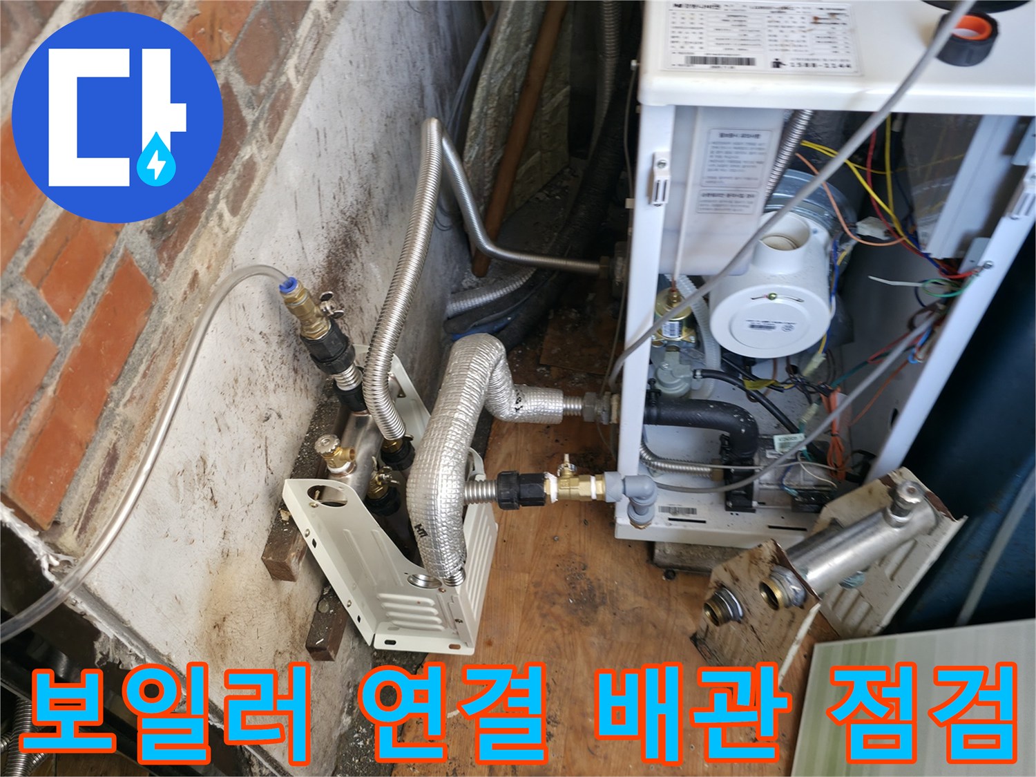 보일러 하단의 금속 배관과 밸브가 복잡하게 연결된 모습입니다.