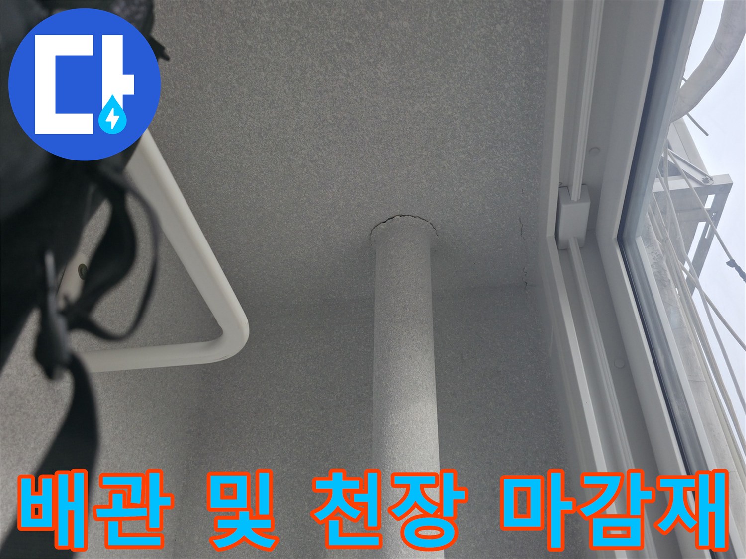 천장 마감재와 수직으로 내려오는 배관의 근접 사진입니다.