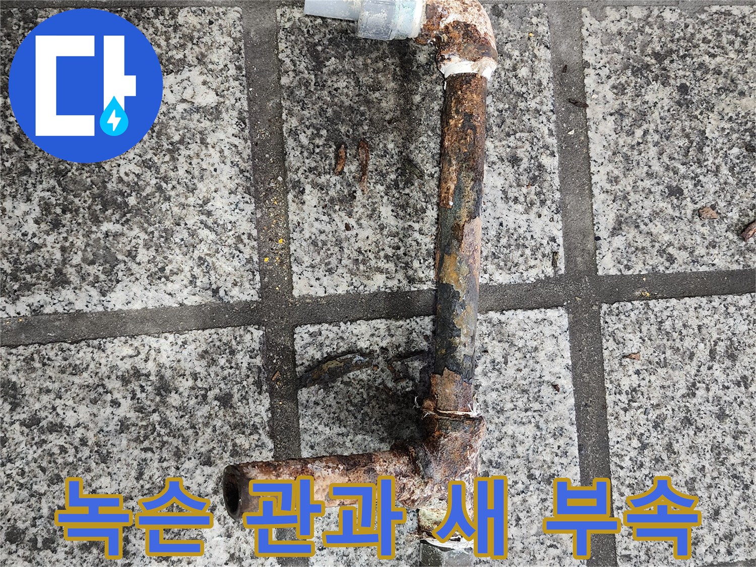 오래된 녹슨 관 옆에 깨끗한 새 부속이 놓여 있는 사진입니다.