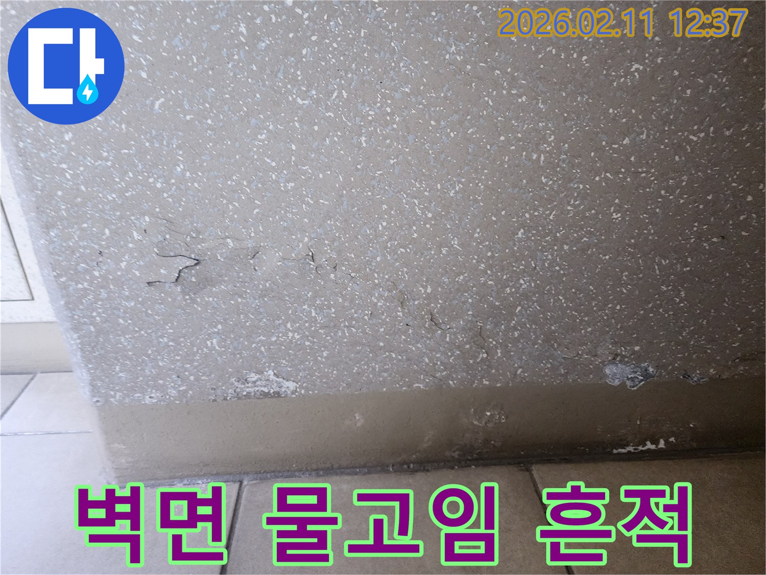 이 사진은 벽과 바닥 경계면에 물이 고여 있고-벽면 마감재가 벗겨진 심각한 누수 상황을 담고 있습니다.